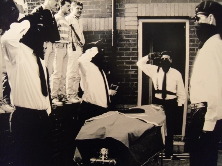 people are standing around a man laying on top of a suitcase