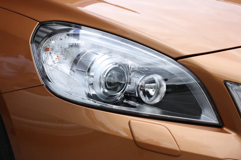 close up of a shiny gold sedan headlight