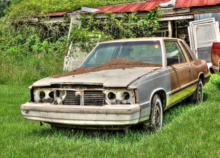 an old rusty car is sitting outside in grass