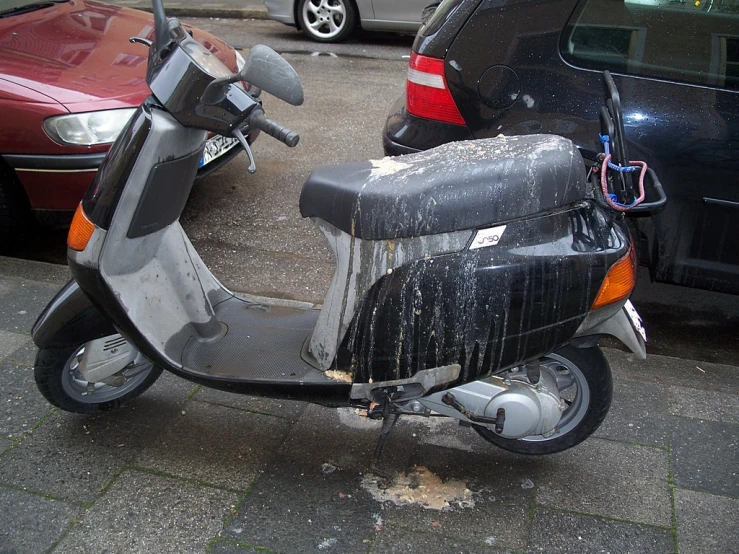 a scooter parked next to cars in front of them