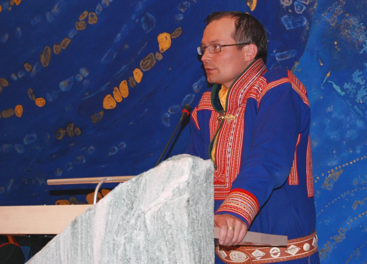 a man standing at a podium in front of a blue wall