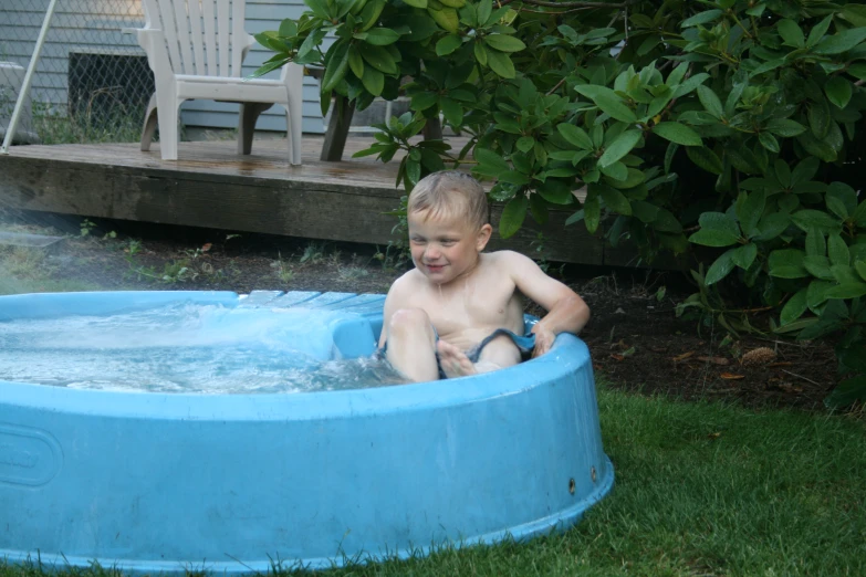 a child sitting in a small pool with green water