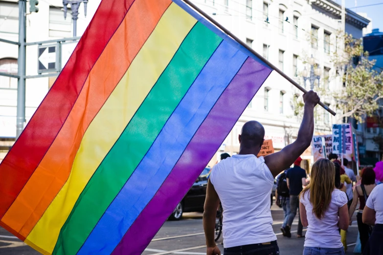 a man holding a rainbow flag at the streets