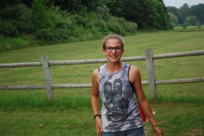 a smiling woman standing in front of a fence