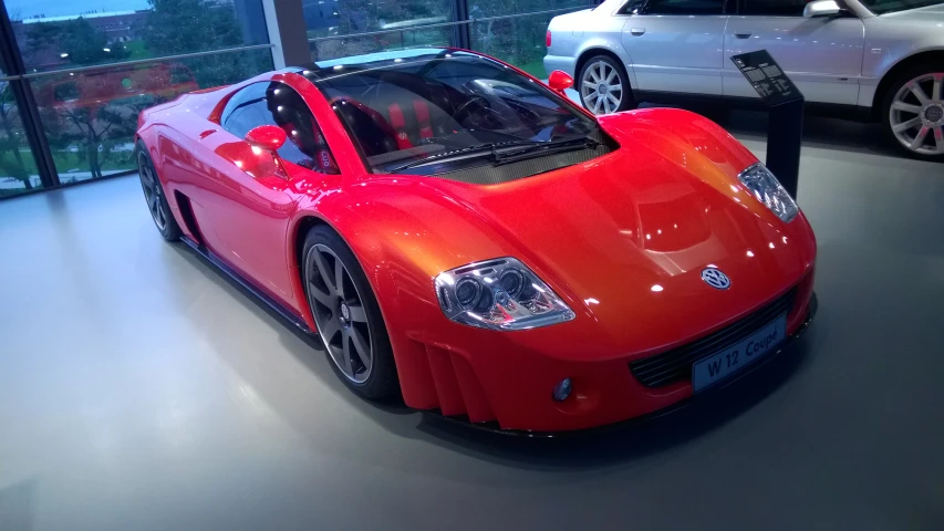 a shiny orange and red sports car next to a silver car