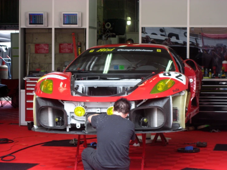 two men are sitting on a ladder as they do work on a car