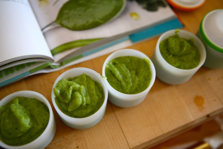 seven small white cups with a few green dips