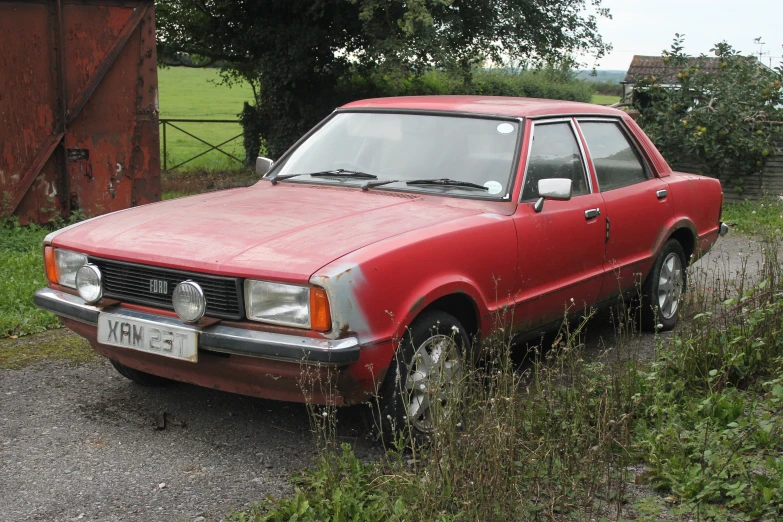 a red car is parked in the gravel