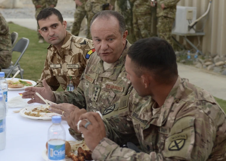 army officers are all enjoying lunch together at a table