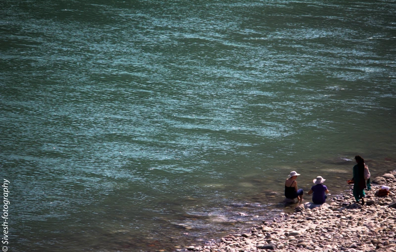 people are standing in the water by a rock shore