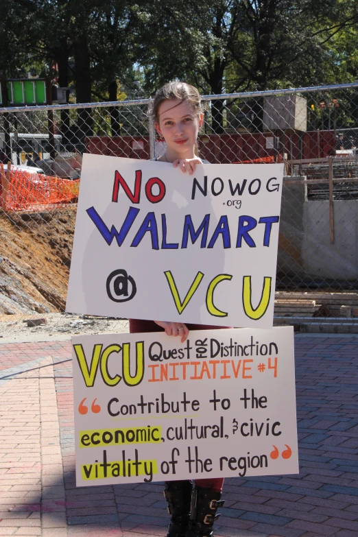 a young woman holds up a sign reading no walmart
