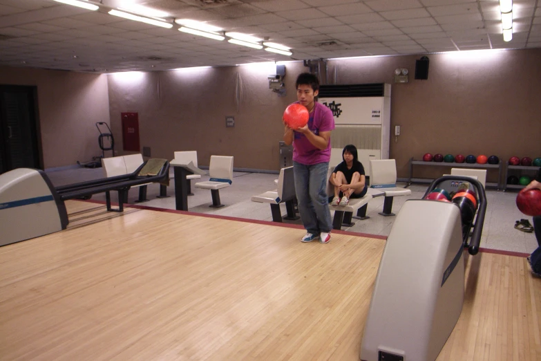 a man holding a frisbee in front of a bowling court