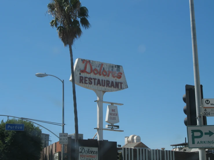 a restaurant sign next to a traffic signal and palm tree