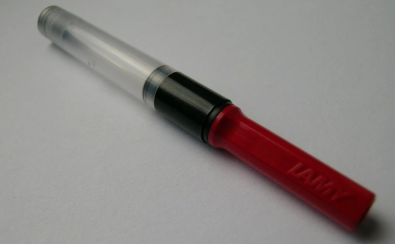 a red and silver fountain pen sitting on top of a table