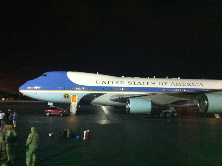 people are standing on the tarmac as an airplane lands