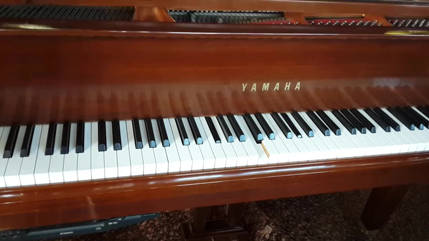 a shiny brown piano has a yamaha sign on it