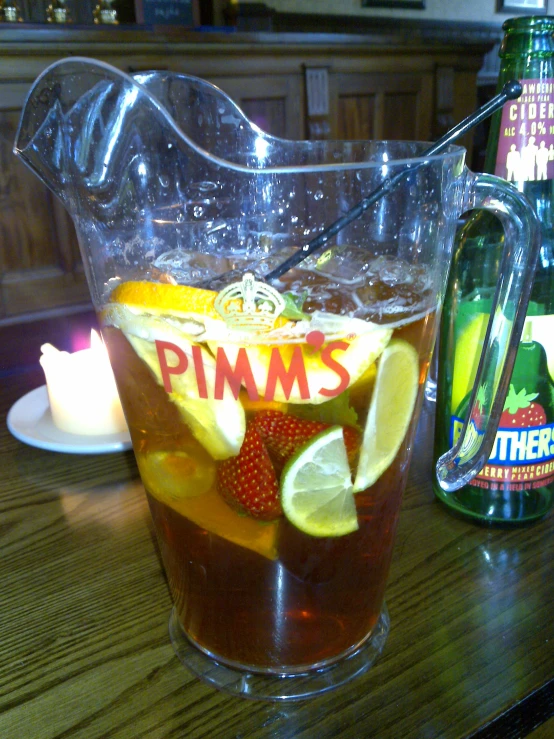 a glass pitcher sitting next to a bottle on top of a wooden table