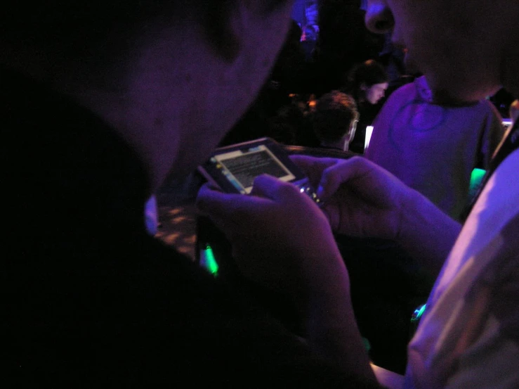 a man is holding a smart device at a concert