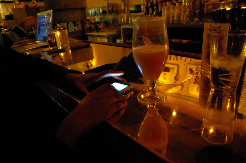 a person is holding an cell phone while drinking a drink