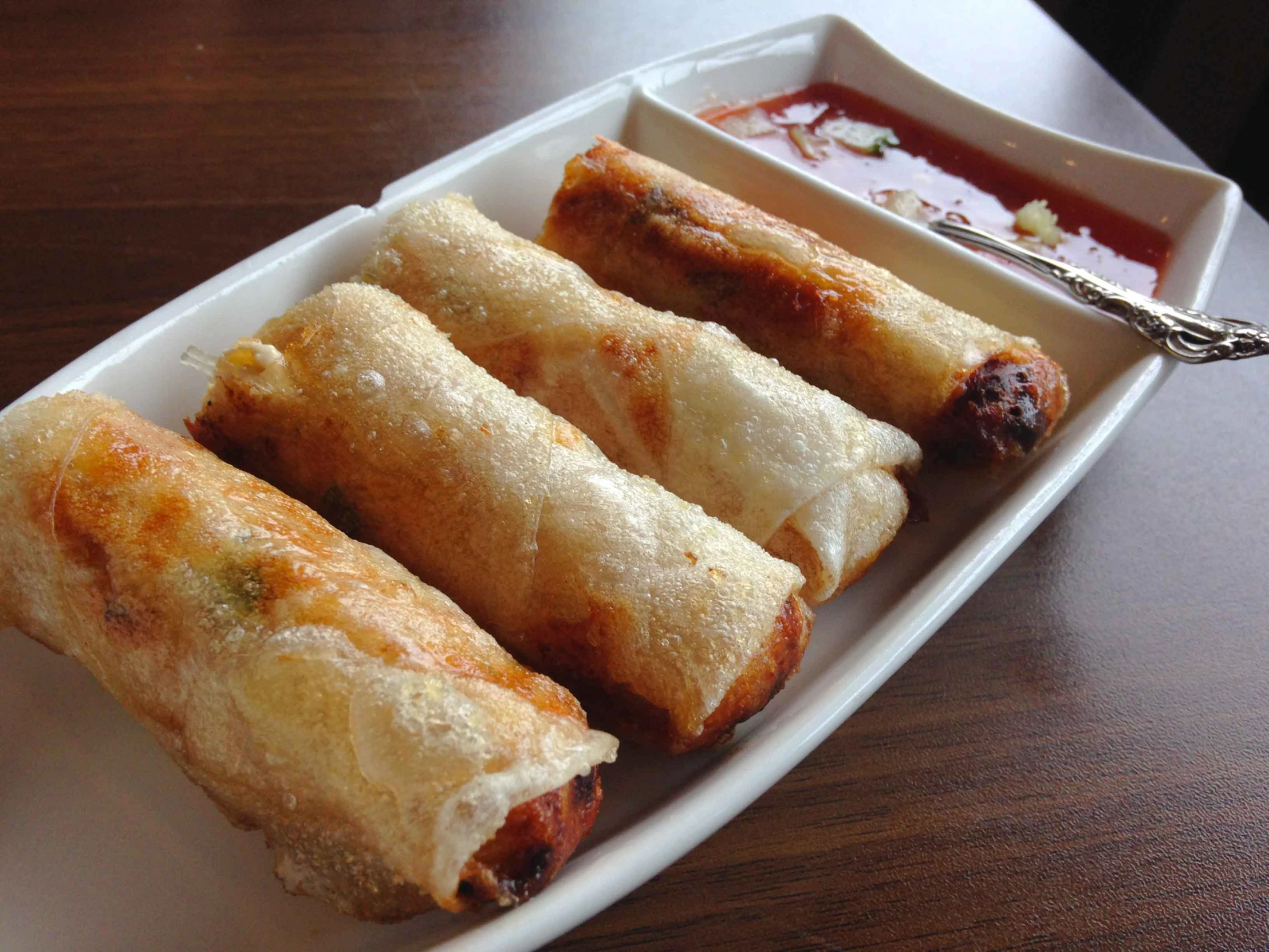 three fried rolls sitting in a dish with dipping sauce