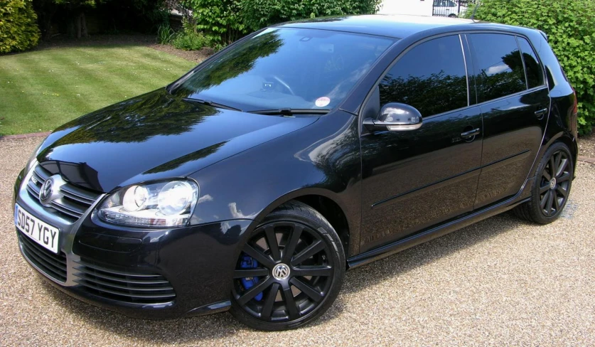 a black golf in a driveway next to a house