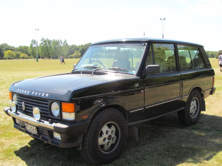 an old black car parked in the grass