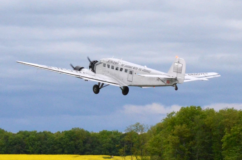 a small aircraft flying in front of some trees