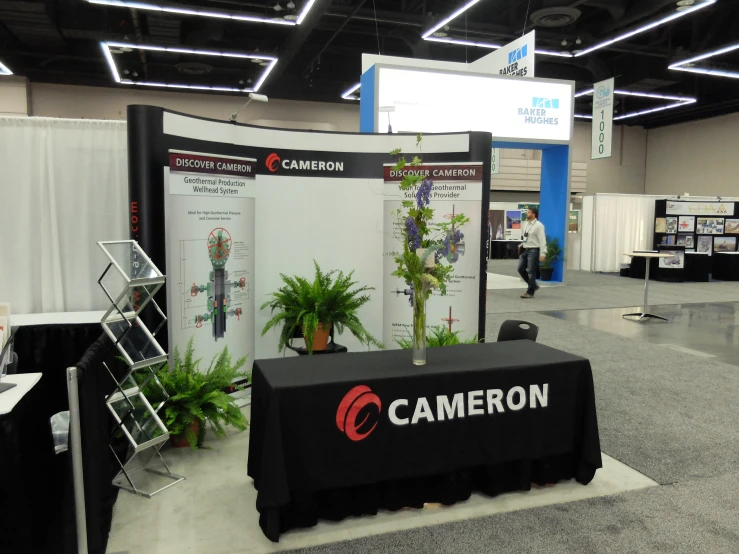 a booth with two large plants behind a table