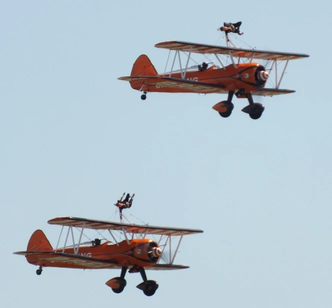 two old style airplanes flying next to each other in the sky