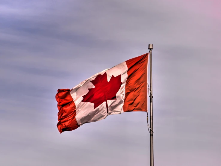 a canada flag waving against a cloudy sky