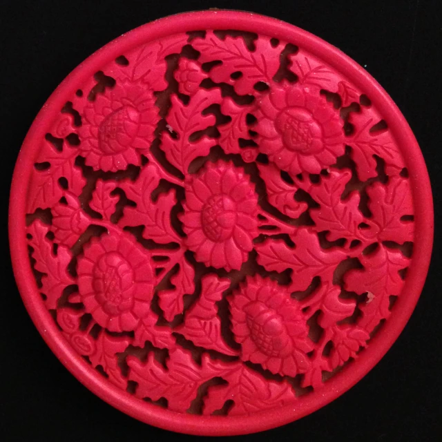 a pink circular piece with flowers carved in it