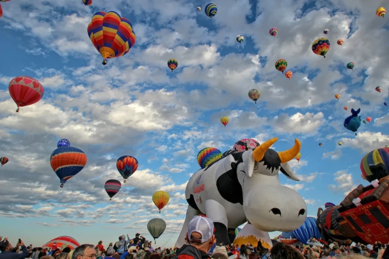 a large group of  air balloons that look like cows flying in the sky