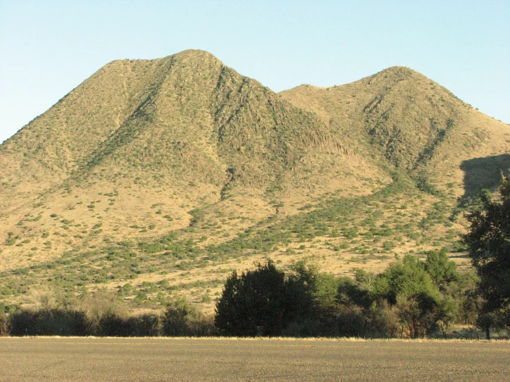 a large rocky mountain behind a field