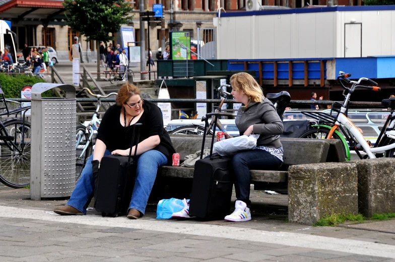 two women on a bench sitting next to a bike