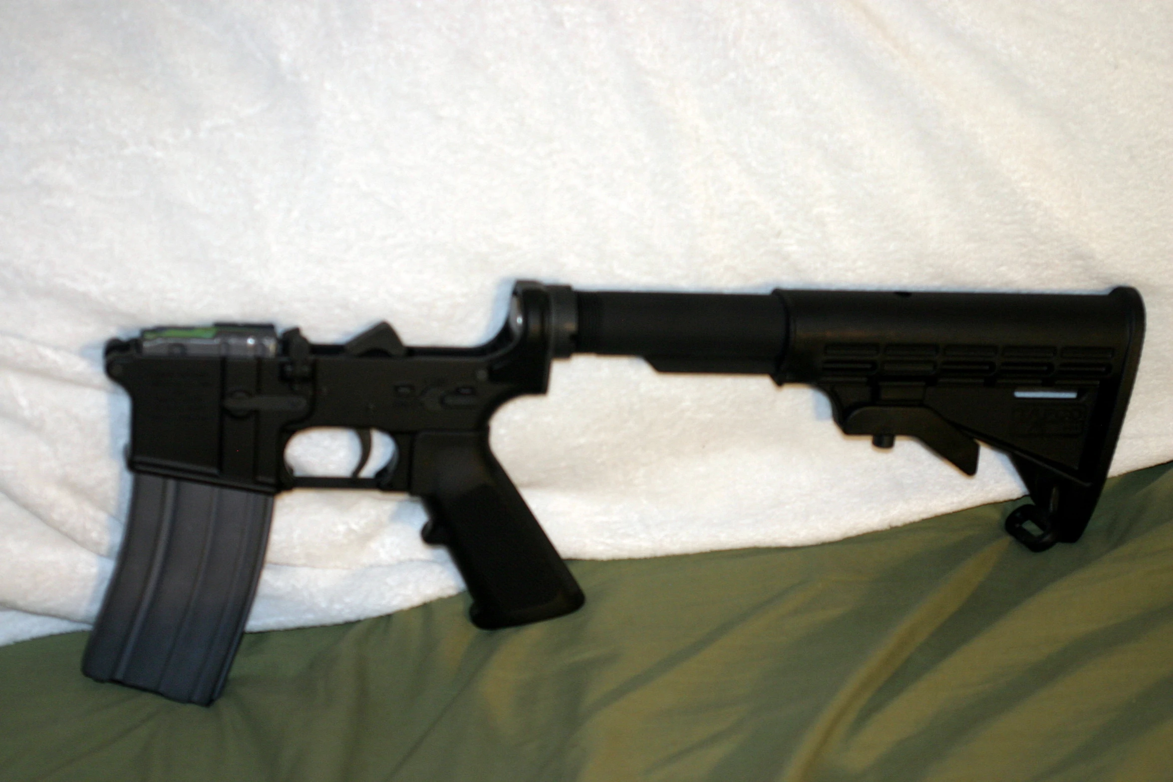a black gun laying on top of a bed