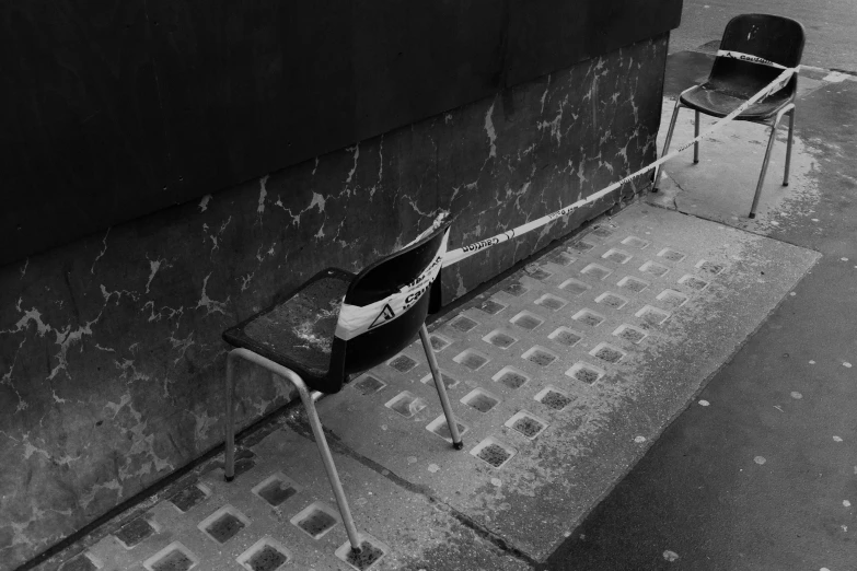 a black and white image of chairs on a city street