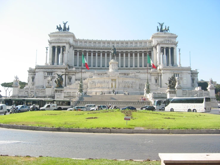 the front view of a large and ornate building with multiple flags on it