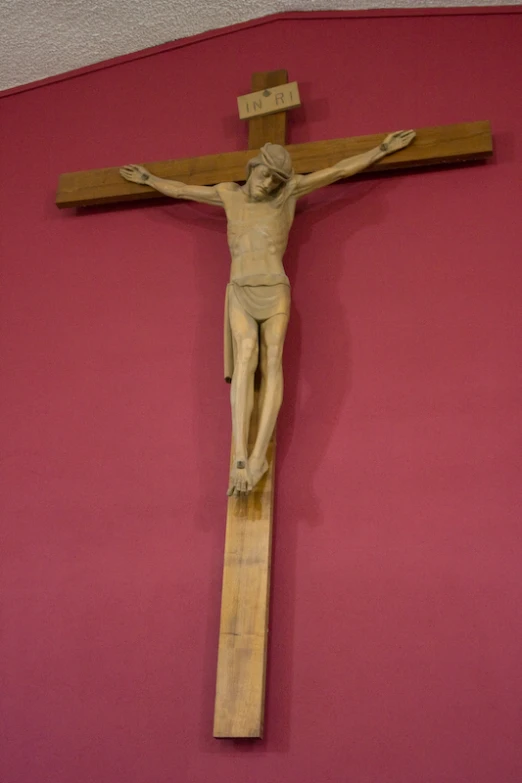 a wooden cross on a pink wall in a room