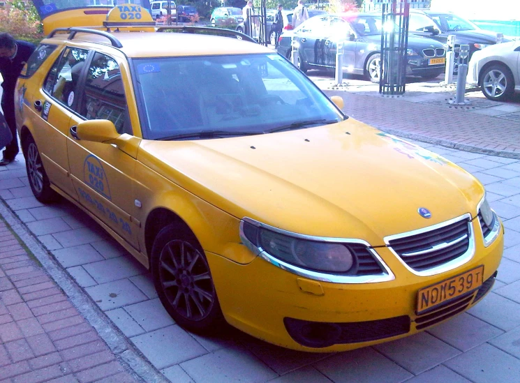 a yellow car and a person waiting to get onto it