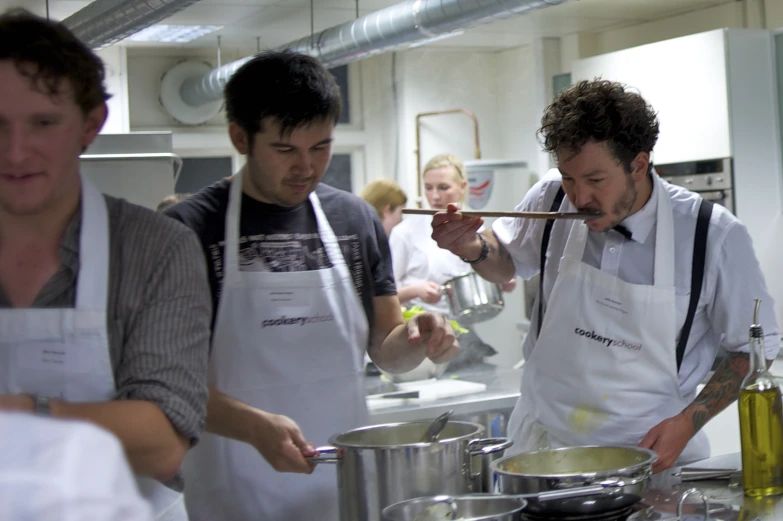 three chefs are preparing food in an industrial kitchen