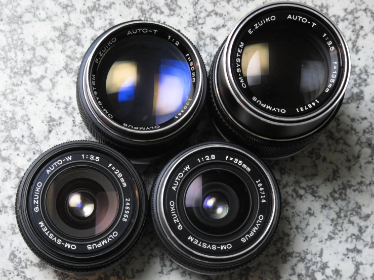 four camera lenses are sitting on a granite counter top