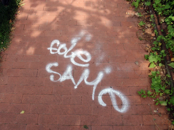 a brick walkway with white spray painted graffiti and the words boo boo say do