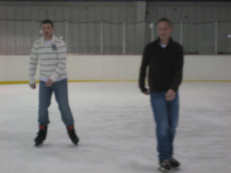 two men skating on an ice rink, one is walking