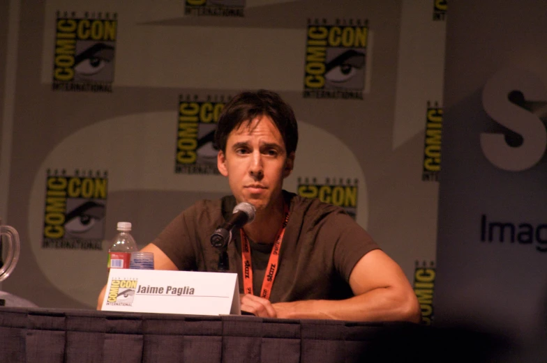 a man in black shirt sitting at a podium