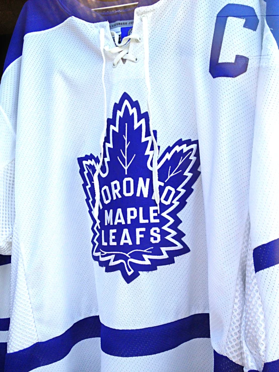 a maple leaf hockey jersey is hanging up for display