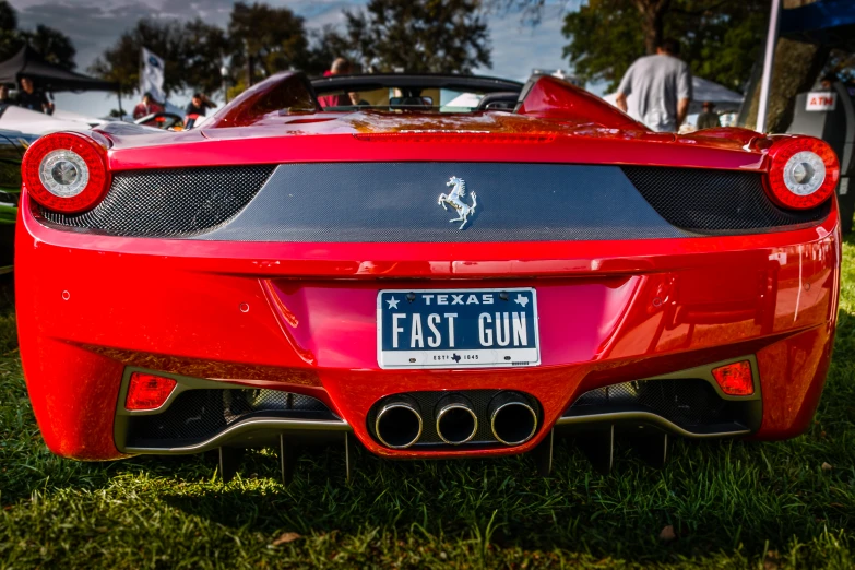 a red ferrari sports car with a license plate parked in the grass