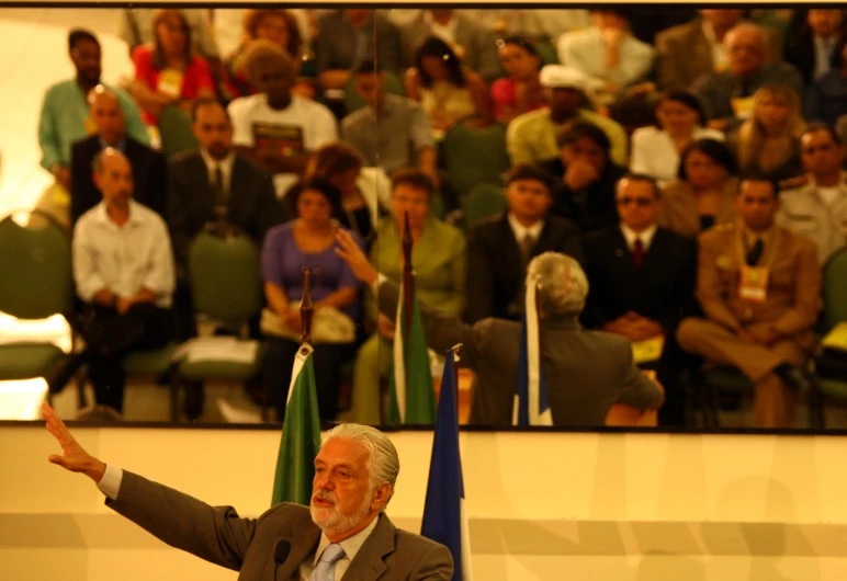 an older man is giving a speech in front of a crowd