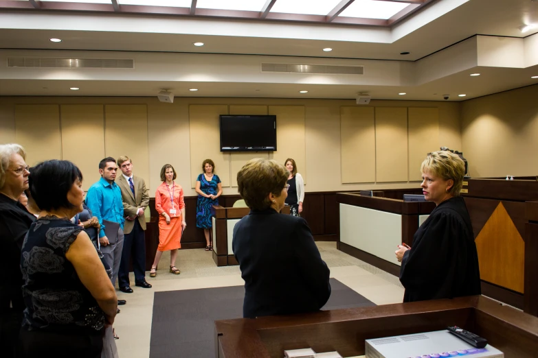 several woman and two men are talking to one another in a courtroom