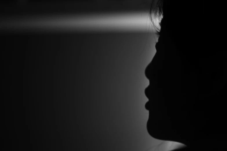 a woman in the shadows with her head tilted to her right