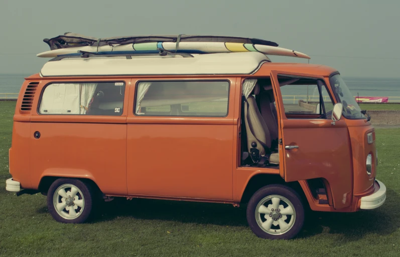 an orange and white van with surfboards on top